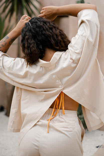 Femme portant une chemise dos ouvert beige. Collection printemps/été, mode éthique et féminine, fabriquée au Portugal avec des tissus dormants. 