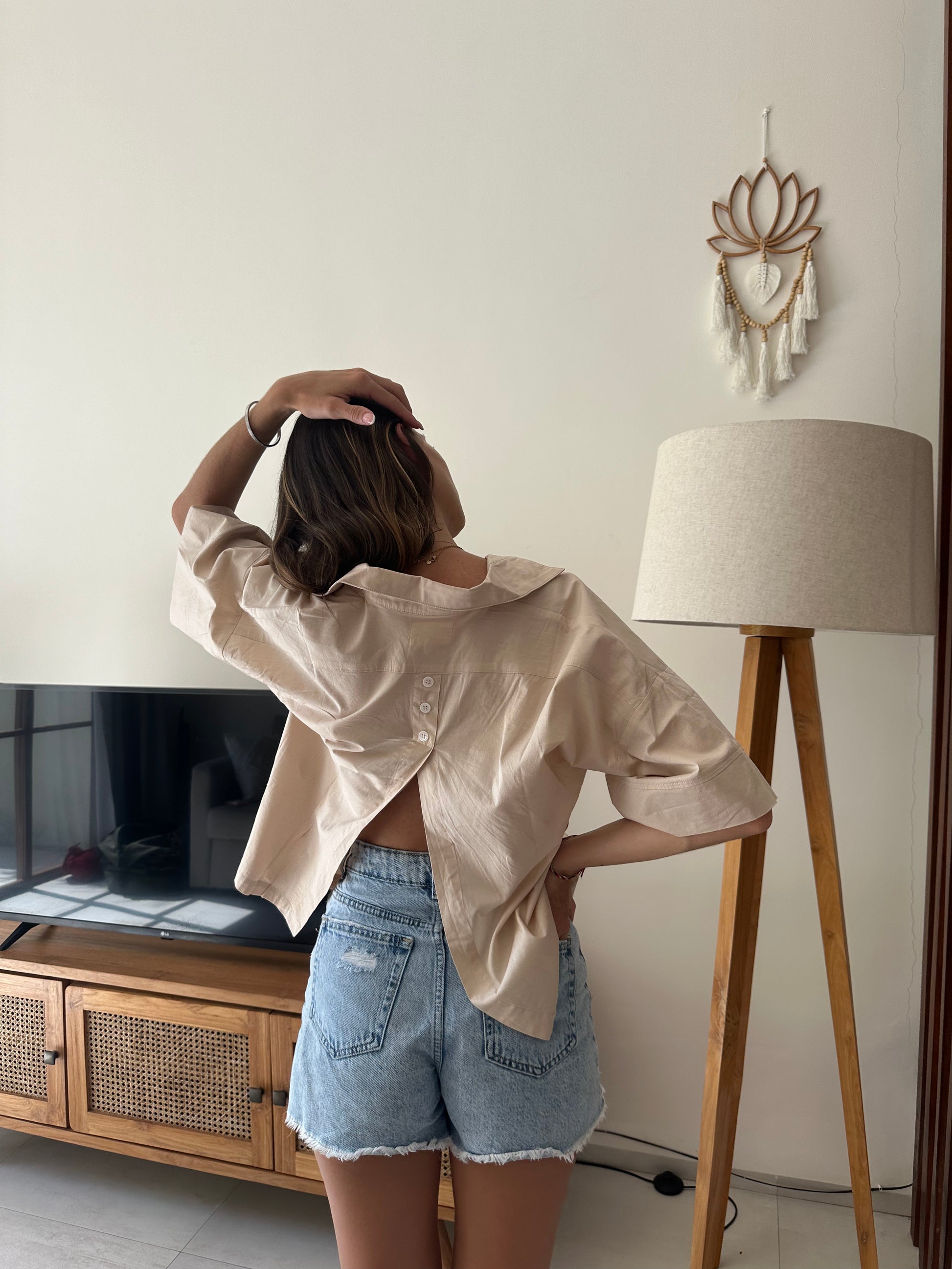 Femme portant une chemise dos ouvert beige. Collection printemps/été, mode éthique et féminine, fabriquée au Portugal avec des tissus dormants. 