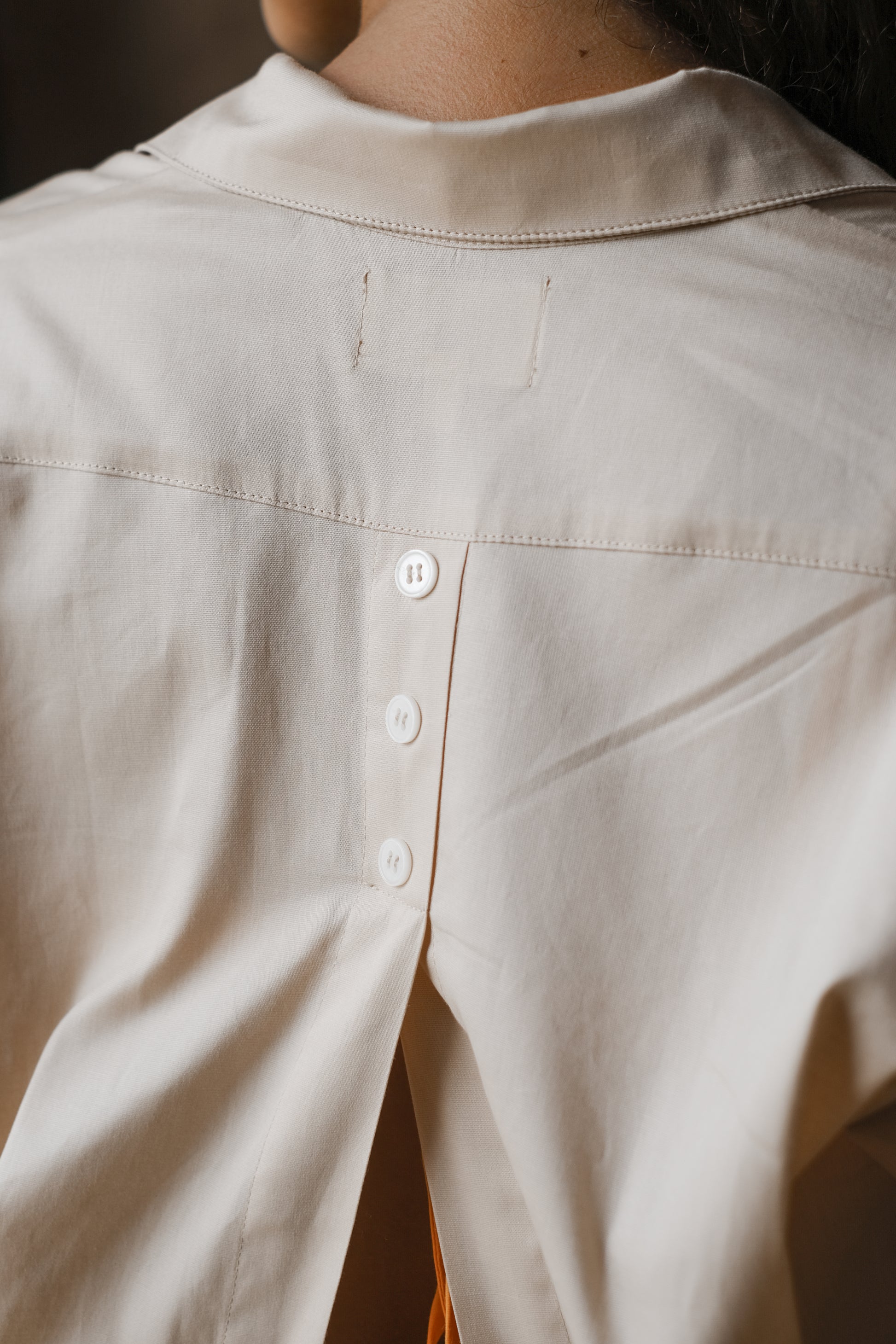 Femme portant une chemise dos ouvert beige. Collection printemps/été, mode éthique et féminine, fabriquée au Portugal avec des tissus dormants. 