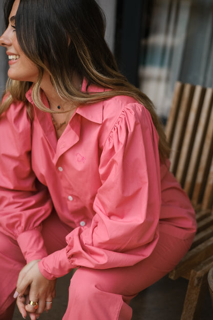 Femme portant une chemise oversize rose framboise avec des manches bouffantes et un pantalon tailleur rose framboise. Collection printemps/été, mode éthique et féminine, fabriquée au Portugal avec des tissus dormants.