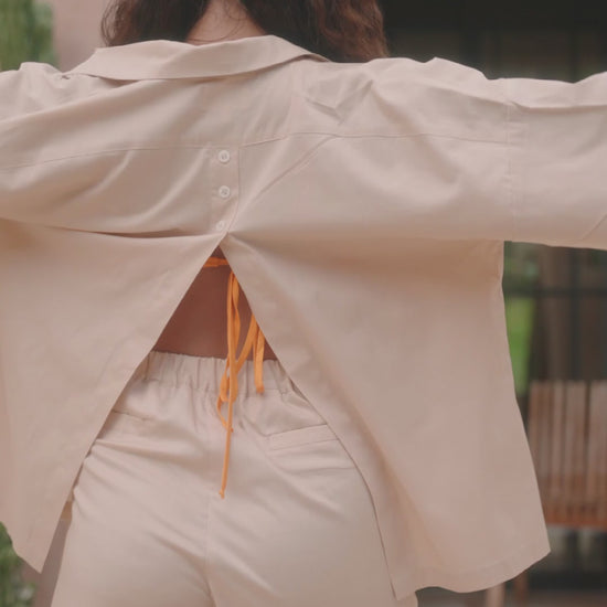 Femme portant une chemise dos ouvert beige. Collection printemps/été, mode éthique et féminine, fabriquée au Portugal avec des tissus dormants.