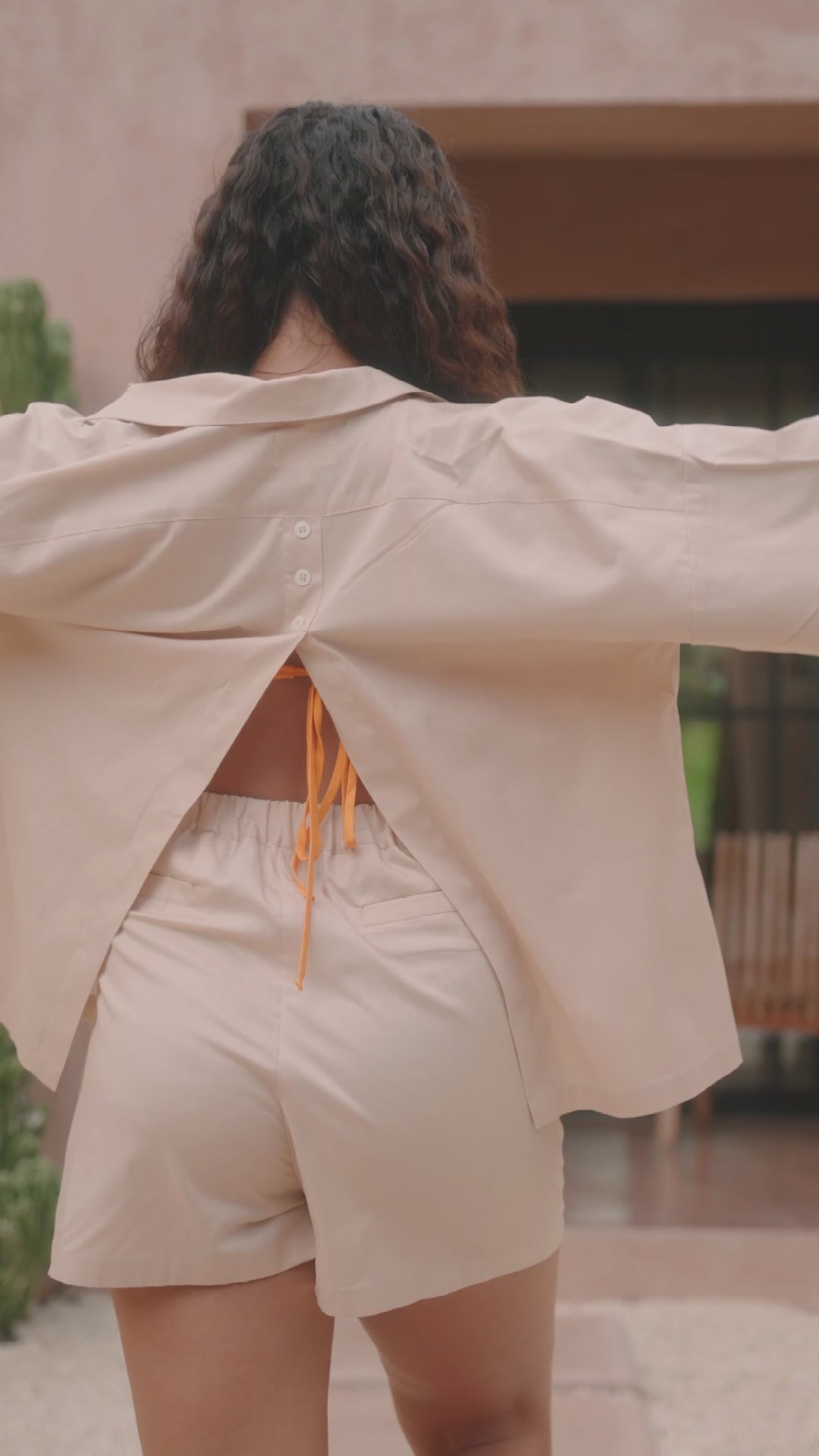 Femme portant une chemise dos ouvert beige. Collection printemps/été, mode éthique et féminine, fabriquée au Portugal avec des tissus dormants.